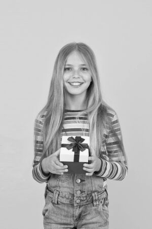 Bought a present. Small child prepare present pack. Little girl smile with wrapped present. Happy kid hold present box on boxing day. Birthday anniversary. Christmas and New Year. Holiday saleの写真素材