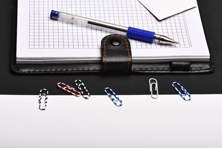Office tools on black and white background. Blank cards, pen, paper clips and organizer, top view. Stationery and leather covered notebook with blank pages. Business and work concept.の写真素材