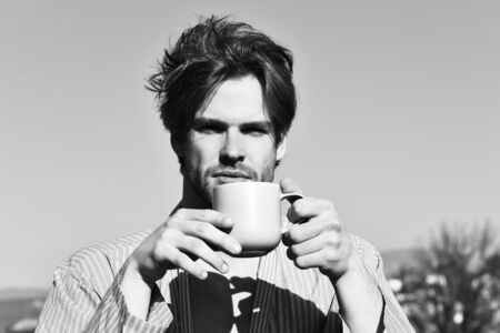 Caucasian macho in blue striped pajamas holding cupの写真素材