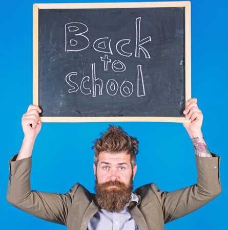 Teacher bearded man holds blackboard with inscription back to school blue background. Teacher with tousled hair stressful about school year beginning. Teaching stressful occupation. Do not be upsetの写真素材
