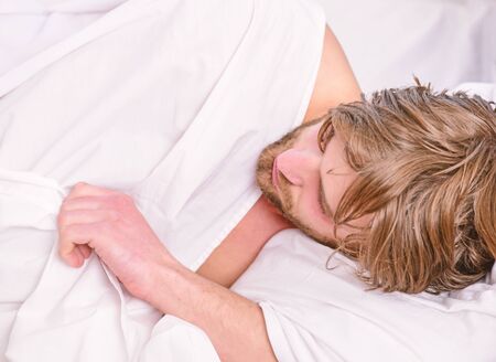 Cheerful young man is waking up after sleeping in the morning. Bare feet of a man peeking out from under the cove. Top view of sexy muscular young man sleeping in bed.の写真素材