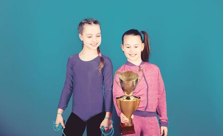 Sport success. victory of teen girls. Winners in competition. Acrobatics and gymnastics. Little girls hold jump rope. Happy children with gold champion cup. victory sport. victory celebrationの写真素材