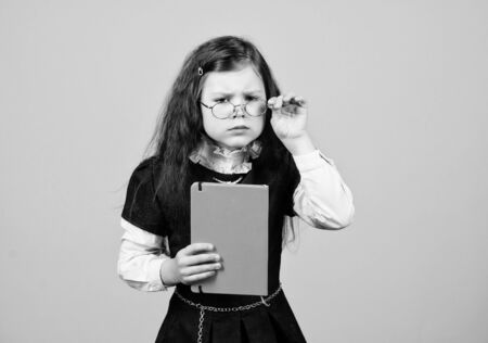 serious small girl wants to be teacher. hometwork. notebook for diary notes. study lesson. knowledge and education. Back to school. small girl with paper folder. Confident graduateの写真素材