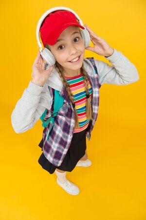 Cute hipster teenager listening music headphones yellow background. Cool schoolgirl. Teens fashion....