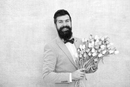 bride groom at wedding party. bearded man in bow tie with tulip flowers. womens day. Formal mature businessman spring bouquet. 8 of march. love date with flowers. Birthday. Capturing a happy momentの写真素材