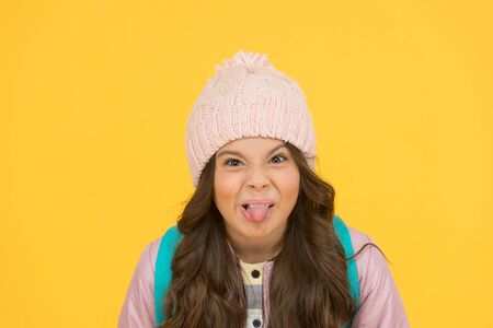 Ugh, yuck. Little schoolchild stick tongue. Little kid make grimace yellow background. Little girl back to school. Little child with autumn lookの写真素材
