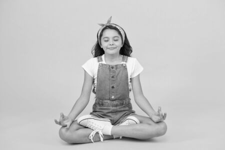 Relax and get comfortable. Small girl sit in yoga posture on yellow background. Little child enjoy yoga training. Yoga meditation. Meditation or yogaの写真素材