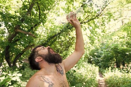 Summer heat. Man thirsty sweaty hipster naked in forest. Heat concept. Bearded tattooed guy relax in nature hot summer day. Hipster wet skin and hair survive heat. Vacation resort. Extreme heatの写真素材