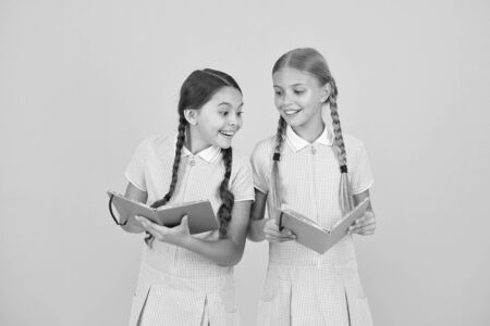Excited about knowledge. old school. happy friends in retro uniform. vintage kid fashion. back to school. small girls hold notepad. encyclopedia book for children. small girls love literatureの写真素材