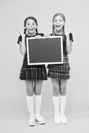Join school club. Pupils community. Cheerleading classes. School schedule. School girls cute pupils red uniform hold blackboard copy space. School announcement concept. Classmates initiative teamの写真素材