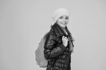 Backpack for keeping belongings secure on the go. Little child wear school backpack on yellow background. Small girl travelling with backpack on autumn holidays. Her backpack is as practical as cuteの写真素材