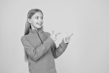 Order and buy it. Happy child present product on yellow background. Little girl pointing fingers at something. Product promotion. Product advertising. Promoting product or service, copy spaceの写真素材