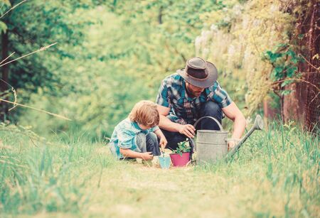 Eco farm. watering can, pot and hoe. Garden equipment. small boy child help father in farming. father and son in cowboy hat on ranch. happy earth day. Family tree nursering. Help and support.の写真素材