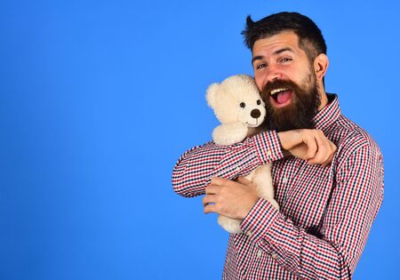 Guy with pleased happy face plays with white soft toy.の写真素材