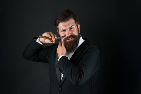Manual shaving. Bearded man shave facial hair dark background. Businessman hold shaving tool. Professional shaving from master barber. Shaving with straight razor. Shave barbershopの写真素材