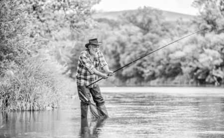 Mature man fishing. Male leisure. Fisherman with fishing rod. Senior man catching fish. Activity and hobby. Fishing freshwater lake pond river. Happiness is rod in your hand. Retired fishermanの写真素材