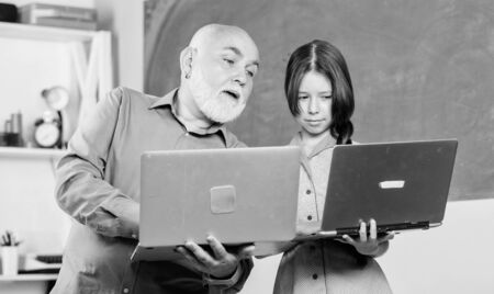 together we can. new technology in learning. school lesson online. Search engine. education blogging. Back to school. mature teacher help pupil girl. small girl with man tutor study on computerの写真素材