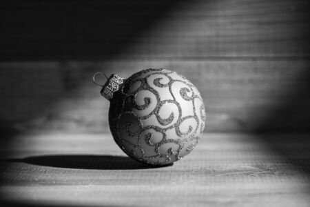 Winter holiday concept. Christmas ball decoration in shadow on vintage wooden background. Decorate christmas tree with traditional toys. Symbol of new year and christmas holidays. Celebrate christmas.の写真素材