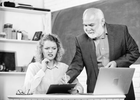 Difficult tasks. Knowledge test. High school college university. Lecturer educator helping student with test. Pass exam. Man mature school teacher and girl with laptop. Final test and graduationの写真素材