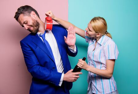 fighting couple. wife wondering why husband came so late. family couple routine. problems in relationship. family psychology. unhappy life. man alcoholic drink wine. woman show time on alarm clockの写真素材