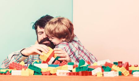 Father and son create constructions. Bearded man and son play together. Surefire ways to bond with your son. Father son game. Dad and kid build plastic blocks. Child care development. Family leisureの写真素材