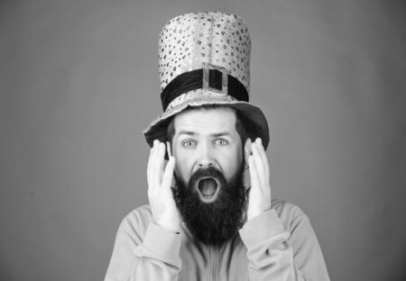 Feeling shocked. Bearded man keeping mouth open while celebrating saint patricks day. Hipster in...