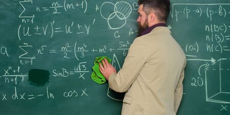 Prepare for lesson. Teacher bearded man cleaning chalkboard background. Teacher wiping chalkboard. School principal. Demanding teacher. Lecturer in classroom. Explaining theory. Teacher hold ragの写真素材