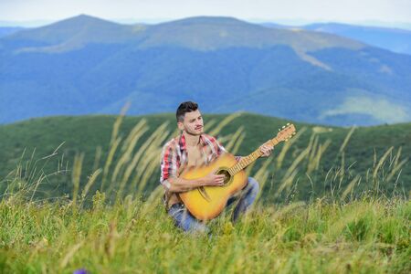 Classic Cool. acoustic guitar player. country music song. sexy man with guitar in checkered shirt. hipster fashion. western camping and hiking. happy and free. cowboy man play guitar outdoorの写真素材