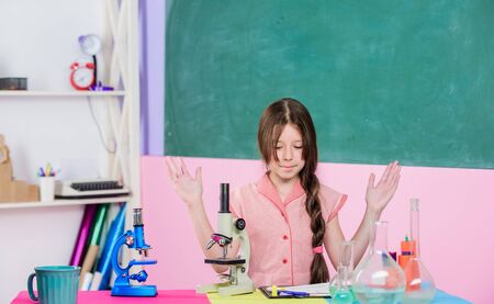 Small girl with microscope. Girl biology class testing tubes. Science lesson. School laboratory....