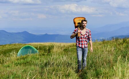 Music makes me stronger. country music song. cowboy man with acoustic guitar player. hipster fashion. happy and free. western camping and hiking. sexy man with guitar in checkered shirtの写真素材