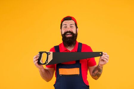 professional repairman in uniform. build and construction. Skilled architect repair and fix. engineer worker career. brutal male worker with saw. man builder yellow background. Future professionの写真素材