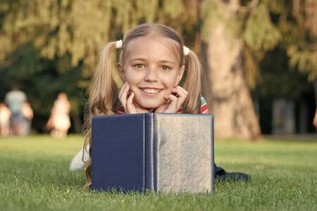Mix of fantasy and reality. Happy girl read fantasy book on green grass. Little child enjoy fantasy story. Concept of fantasy. Imagination and creativity. Leisure timeの写真素材
