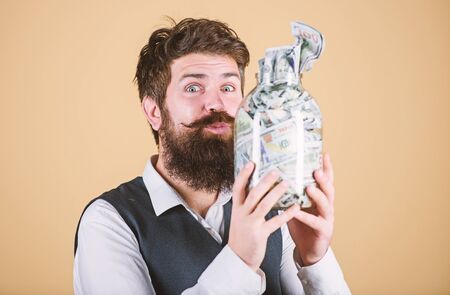 Keeping money in saving bank. Bearded man holding glass jar with paper bank notes. My money going directly into the piggy bank. Bank and bankingの写真素材