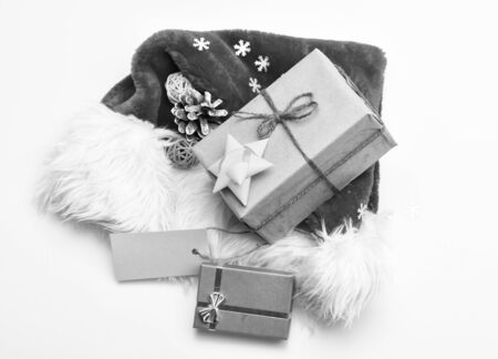 Santa red hat white background top view. Santa hat with christmas gift box. Keep family traditions. Christmas presents from santa. Attributes of winter holidays. New year and christmas celebration.の写真素材