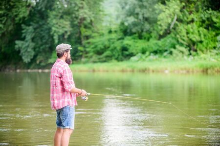dont look back. experienced fisher in water. fisherman show fishing technique use rod. man catching fish. mature man fly fishing. sport activity and hobby. Successful fly fishing. summer weekend.の写真素材