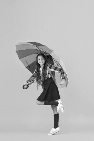 Enjoying autumn day. color up life. go to school. good weather forecast. under my umbrella. small girl bright parasol. fall style. stay positive any season. happy child protected rain. rainbow colorsの写真素材