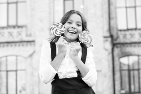Crazy about sweets. Happy kid with candy. School nutrition. Calories and energy. Both mine. Sugar addiction. Cheat meal day. Happy kid with sweet candy. Kid child holding lollipops candy outdoorsの写真素材