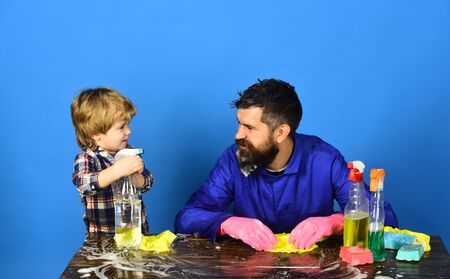 Kid holds spray directed to father. Dad with son