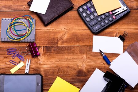 Office tools on wooden background, top view and copy space. Leather wallet and stationery. Business...