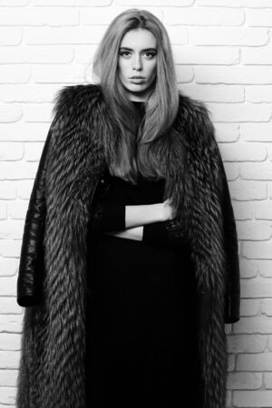 fashionable sexy woman in fur on white brick wall studio backgroundの写真素材