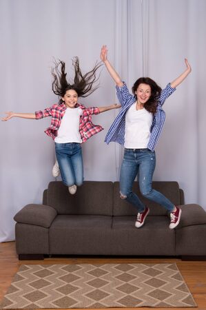 Fun leisure at home. girls party at home. happy sisters jump in freedom sense. mother and daughter having fun on weekend. move in new house. full of energy. real happiness. happy family dayの写真素材