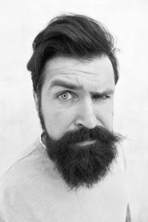 Suspicious look. Perceptions of male beauty. Stylish beard and mustache care. Happy face. Beard fashion barber. Handsome guy. Masculinity concept. Man bearded hipster stylish beard grey backgroundの写真素材