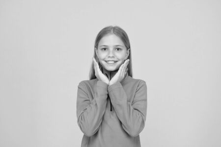Adorable girl beautiful face. Childrens shop store mall. Goods for teens. Upbringing and education. Little girl. Small child on yellow background. Child care concept. Preteen girl smiling expressionの写真素材