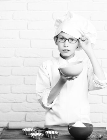 serious boy cute cook chef on brick wall backgroundの写真素材