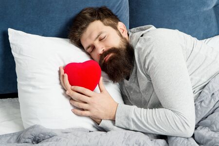 who is my valentine. bearded hipster sleep in bed. Heart filled with love. man feel romance. holidays and surprise concept. romantic morning at home. celebrating Saint Valentines Day. What to expectの写真素材
