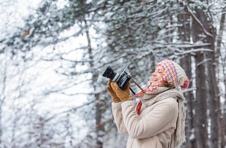 taking picture in winter forest. Photographer photographing on snowy winter day. happy woman warm...