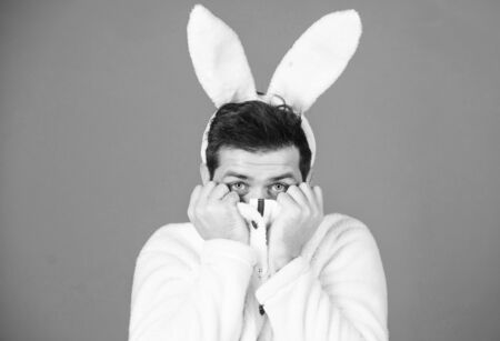 Man handsome face wear white bunny ears. Easter bunny. White bunny symbol of easter holiday. Soft and tender. Guy with long bunny or rabbit ears on violet background. Enjoy tenderness. Cute bunnyの写真素材
