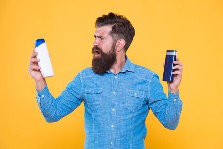 Shampooing hair in salon. Bearded man choose shampoo to use. Daily shampooing habits. After...