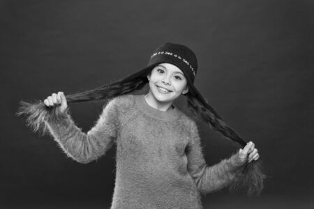Healthier hair from root to tip. Happy child hold long hair. Cute small kid wear warm hat on head. Hair and beauty salon. Winter haircare. Protect your ears and hair from coldの写真素材