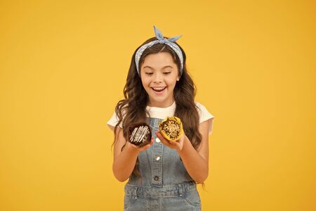Cafe restaurant food. Yummy cupcakes. Bakery and confectionery concept. Kid girl hold glazed muffins. Delicious cupcakes. Happy childhood. Adorable smiling child with cupcakes on yellow backgroundの写真素材